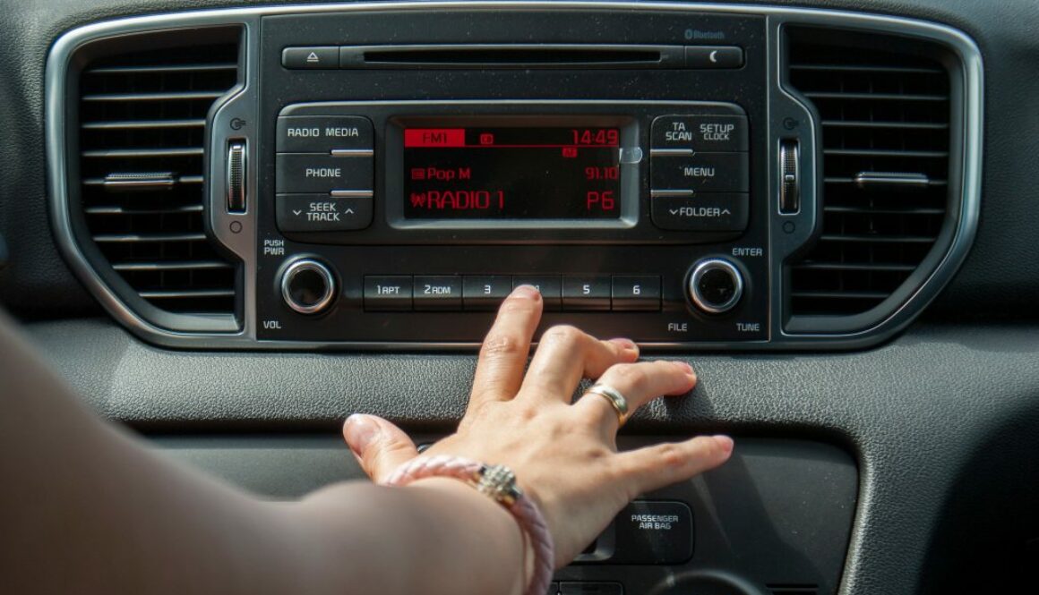 Cropped Hand Of Woman Operating Radio In Car