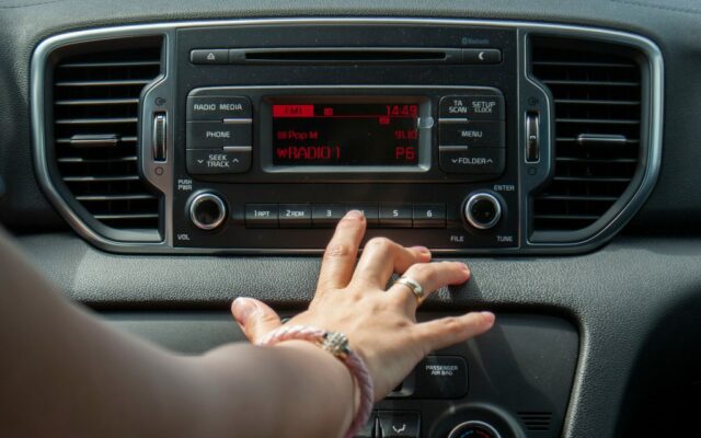 Cropped Hand Of Woman Operating Radio In Car