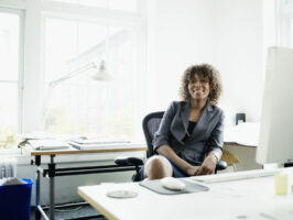 Businesswoman seated at desk in office, smiling