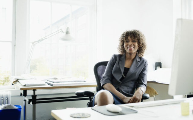 Businesswoman seated at desk in office, smiling